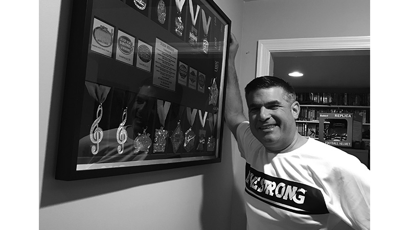 Jason Herman standing in front of large display case of medals