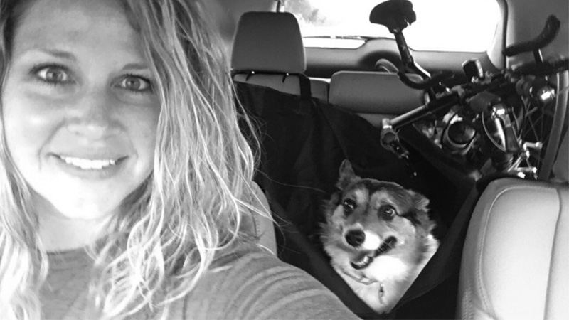 Myranda and her dog in her car in a selfie. She's on the way to a race. You can see the bike in the back of the car.