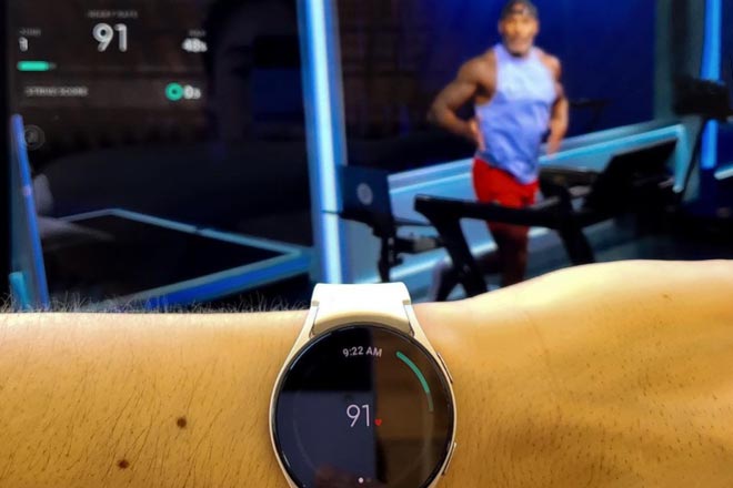 Android watch on a wrist with Adrian Williams in the background in the tread studio