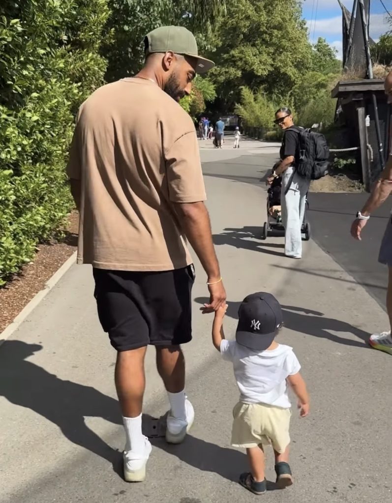 Peloton instructor Jermaine Johnson walking and holding hands with his son Ray