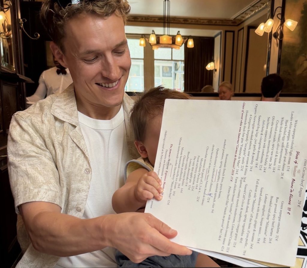 Peloton instructor Matt Wilpers at a restaurant with his son on his lap holding a menu