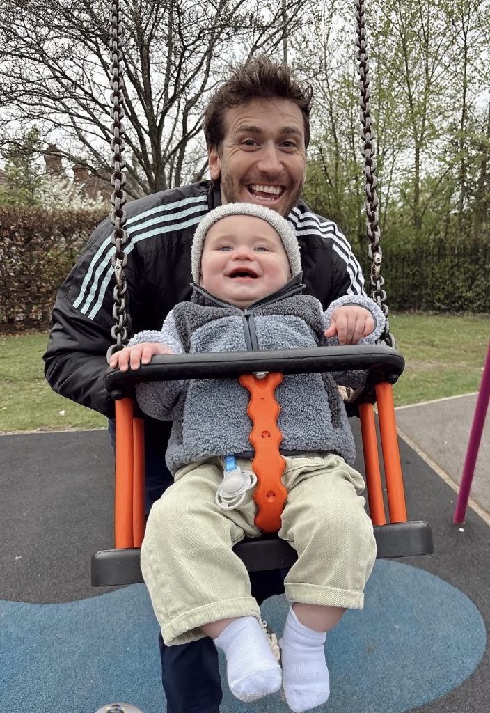 Peloton instructor Bradley Rose pushing his son in a swing.