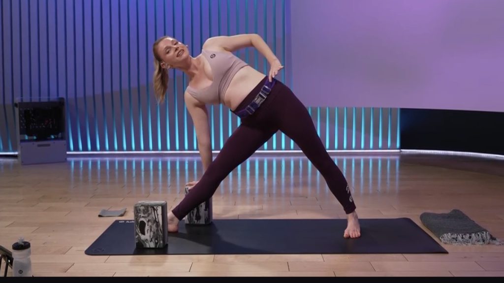 Prenatal Yoga + Pilates class moving through a modified extended triangle pose with a block.