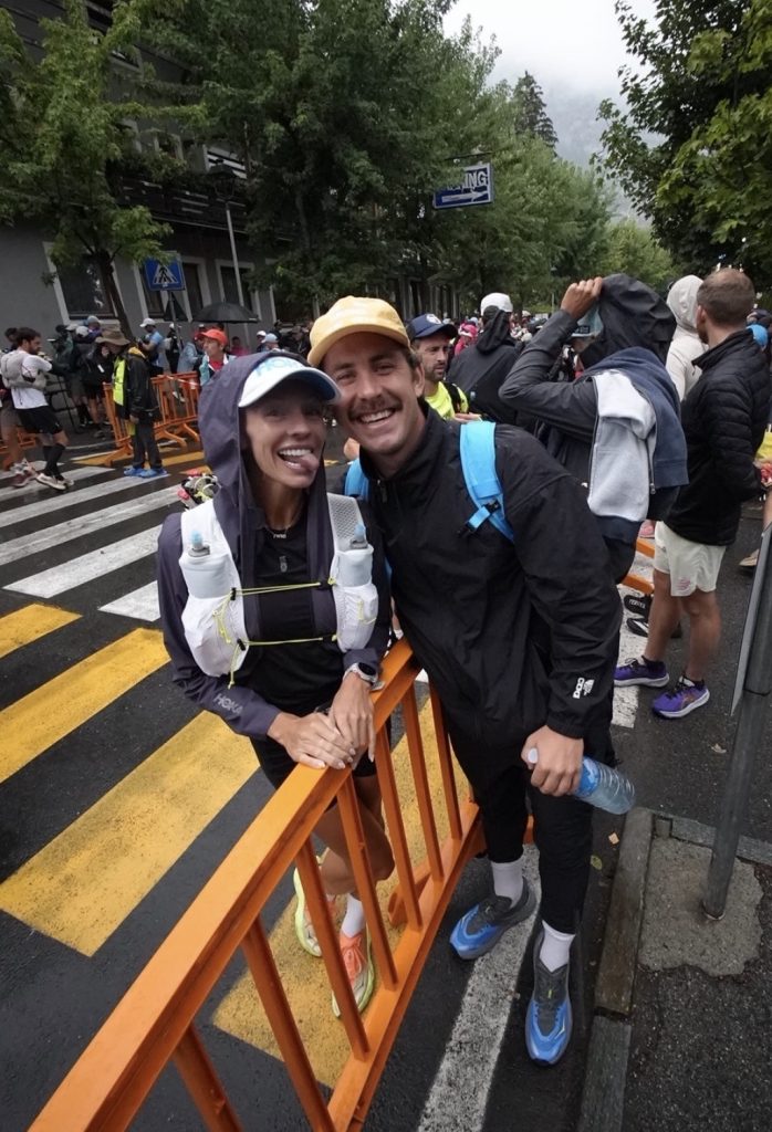 Becs Gentry CCC finish course, rain gear and hydration vest at a barrier with Austin Curtis