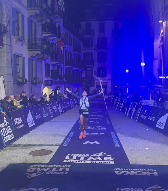 Becs Gentry CCC finish, arms raised in the HOKA UTMB finish chute in Chamonix