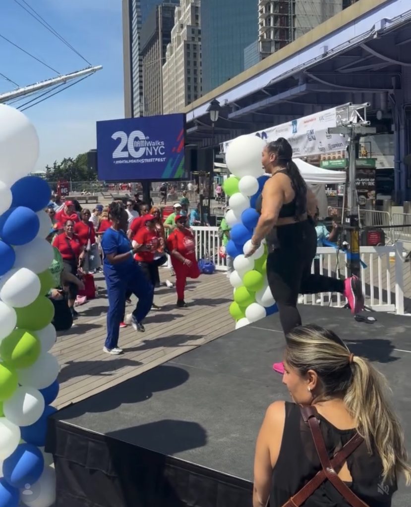 Suicide prevention month spotlight: Ash Pryor leads a warm-up on stage at NAMIWalks NYC.
