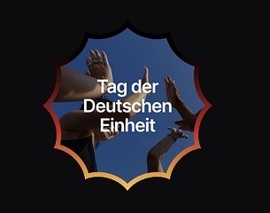 German Unity Day Tag der Deutschen Einheit badge with raised hands against a blue sky