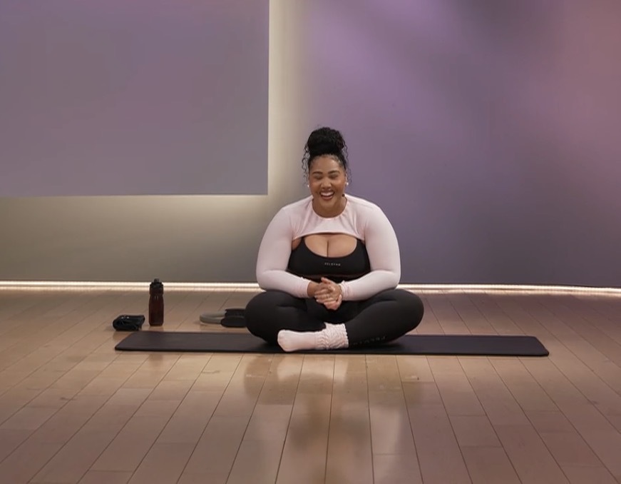 Ash Pryor Pilates class, Ash smiling cross-legged on her mat