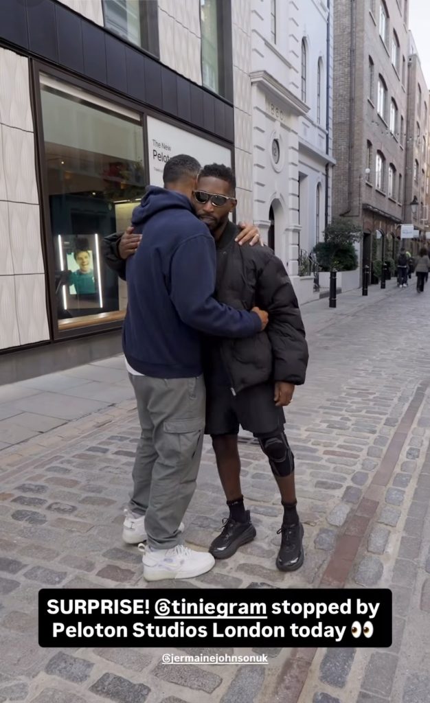 Tinie Tempah Peloton visit begins as Jermaine Johnson hugs Tinie outside Peloton Studios London