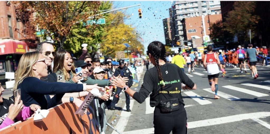 NYC Marathon shakeout run preview showing a runner high-fiving cheering Peloton fans along the TCS New York City Marathon course